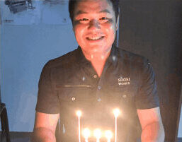 誕生日ケーキのろうそくを持ち、笑顔で写る社員