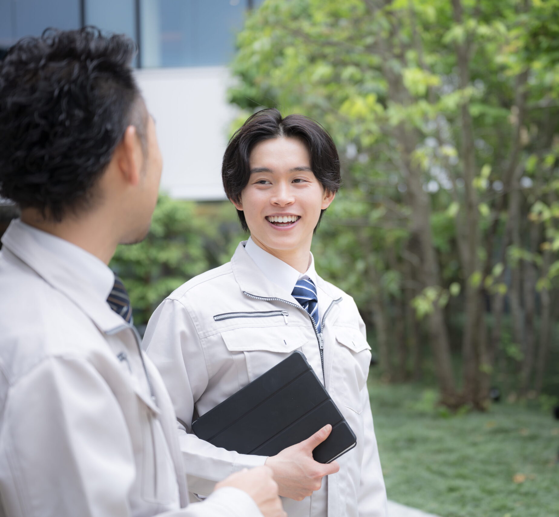 屋外に立つ作業服姿の男性